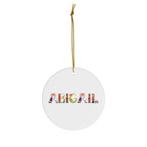White ceramic ornament with text ‘Abigail’ in colourful Christmas themed lettering, with gold hanging loop