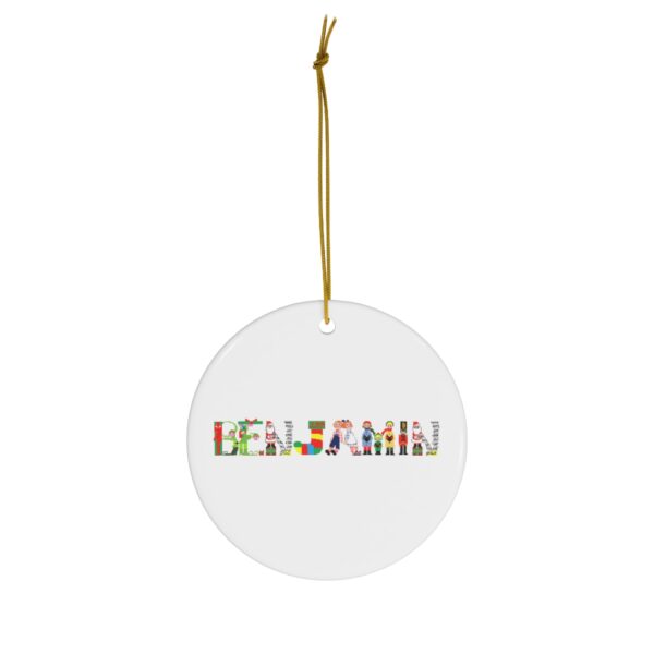 White ceramic ornament with text ‘Benjamin’ in colourful Christmas themed lettering, with gold hanging loop