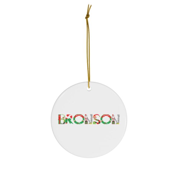White ceramic ornament with text ‘Bronson’ in colourful Christmas themed lettering, with gold hanging loop