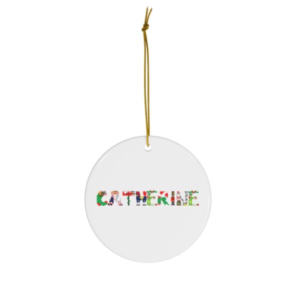 White ceramic ornament with text ‘Catherine’ in colourful Christmas themed lettering, with gold hanging loop