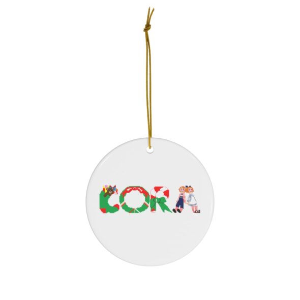 White ceramic ornament with text ‘Cora’ in colourful Christmas themed lettering, with gold hanging loop