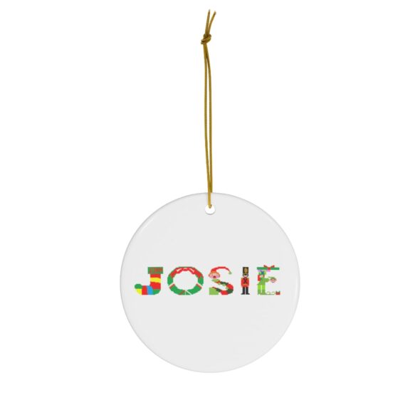 White ceramic ornament with text ‘Josie’ in colourful Christmas themed lettering, with gold hanging loop