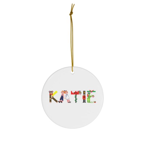 White ceramic ornament with text ‘Katie’ in colourful Christmas themed lettering, with gold hanging loop