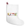 White stocking with text ‘Katie’ in colourful Christmas themed lettering, with red hanging loop