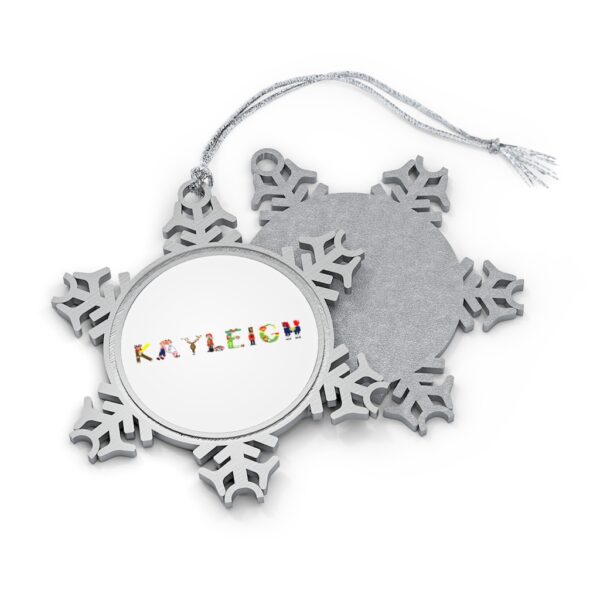 Silver-toned snowflake ornament with white insert with text ‘Kayleigh’ in colourful Christmas themed lettering, with silver hanging loop