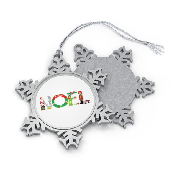 Silver-toned snowflake ornament with white insert with text ‘Noel’ in colourful Christmas themed lettering, with silver hanging loop