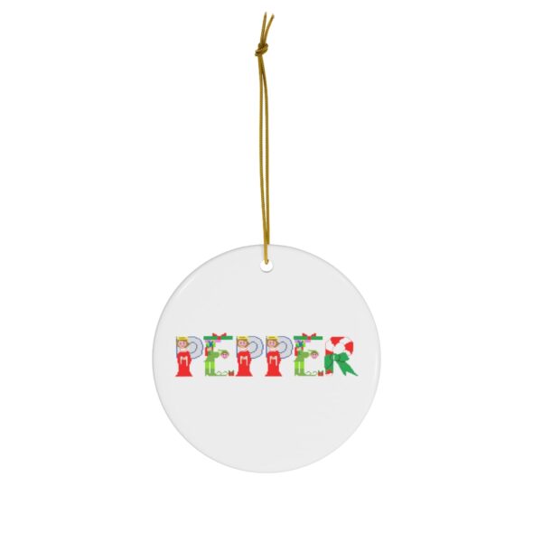 White ceramic ornament with text ‘Pepper’ in colourful Christmas themed lettering, with gold hanging loop