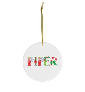 White ceramic ornament with text ‘Piper’ in colourful Christmas themed lettering, with gold hanging loop