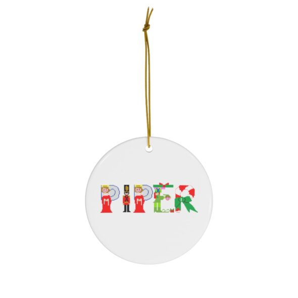 White ceramic ornament with text ‘Piper’ in colourful Christmas themed lettering, with gold hanging loop