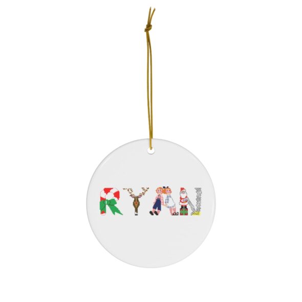 White ceramic ornament with text ‘Ryan’ in colourful Christmas themed lettering, with gold hanging loop