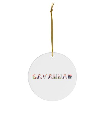 White ceramic ornament with text ‘Savannah’ in colourful Christmas themed lettering, with gold hanging loop