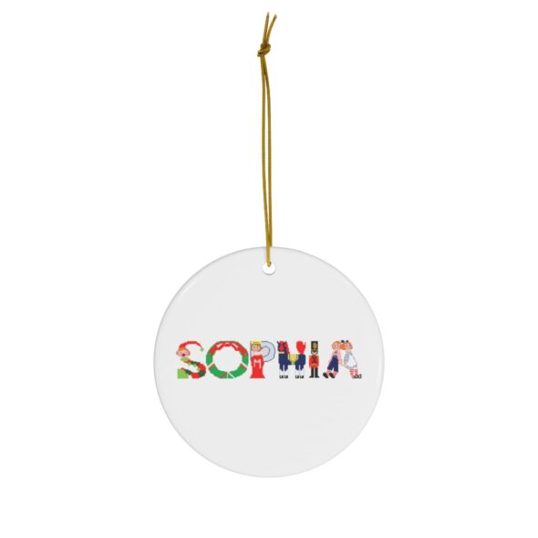 White ceramic ornament with text ‘Sophia’ in colourful Christmas themed lettering, with gold hanging loop