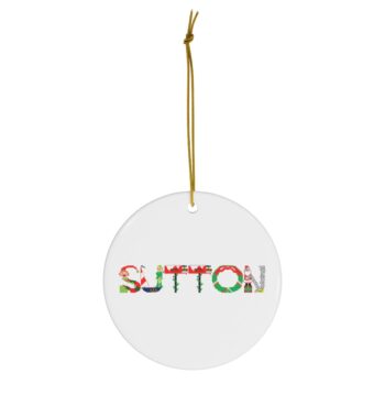 White ceramic ornament with text ‘Sutton’ in colourful Christmas themed lettering, with gold hanging loop