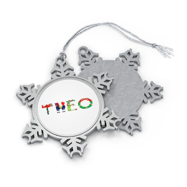 Silver-toned snowflake ornament with white insert with text ‘Theo’ in colourful Christmas themed lettering, with silver hanging loop
