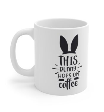 White 11 ounce mug with black bunny ears and. whiskers graphic that reads ‘this bunny hops on coffee’