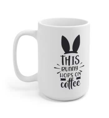 White 15 ounce mug with black bunny ears and. whiskers graphic that reads ‘this bunny hops on coffee’