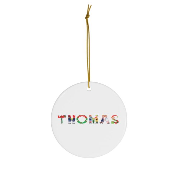 White ceramic ornament with text ‘Thomas’ in colourful Christmas themed lettering, with gold hanging loop